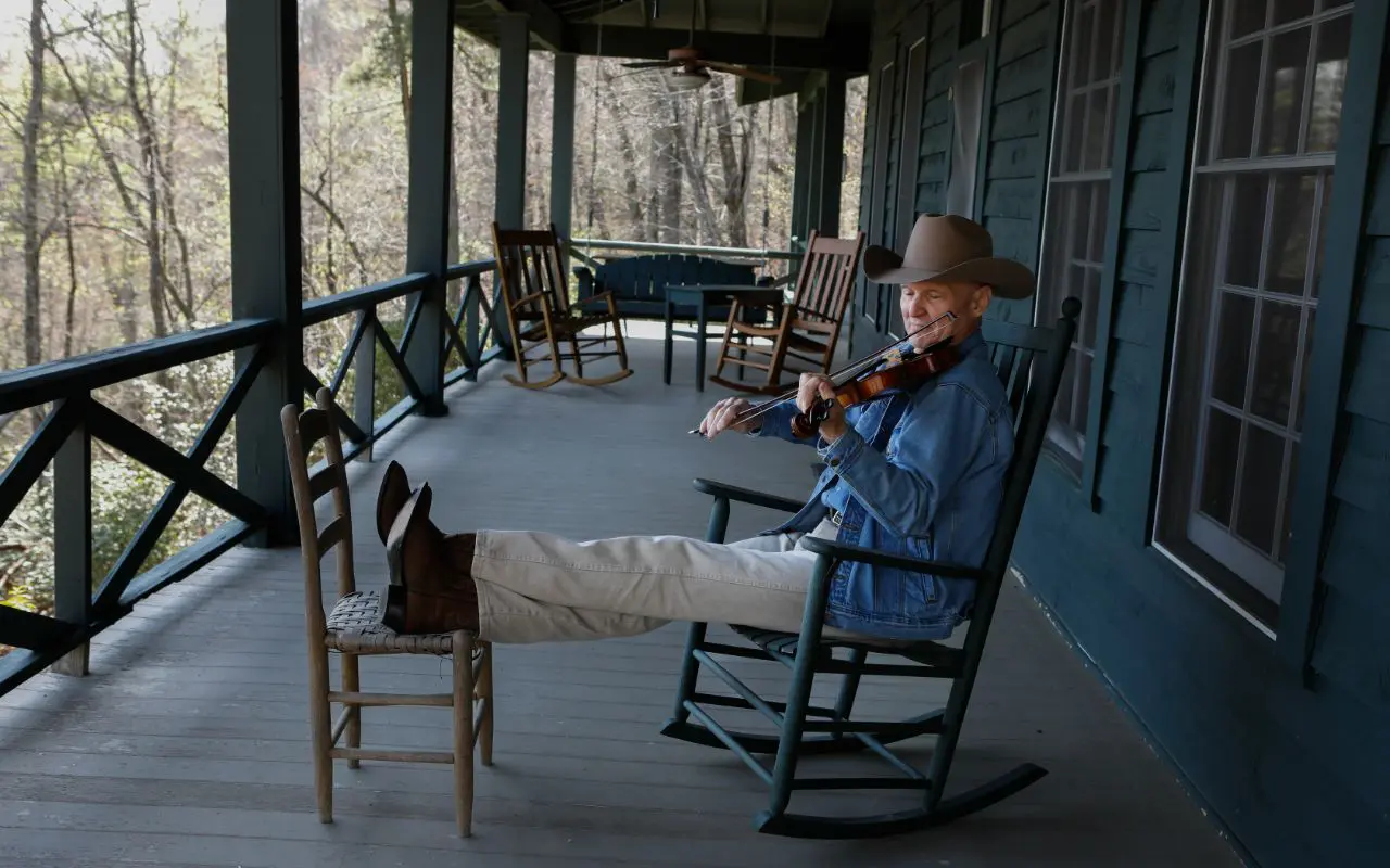 A man playing the violin on an outdoor porch.