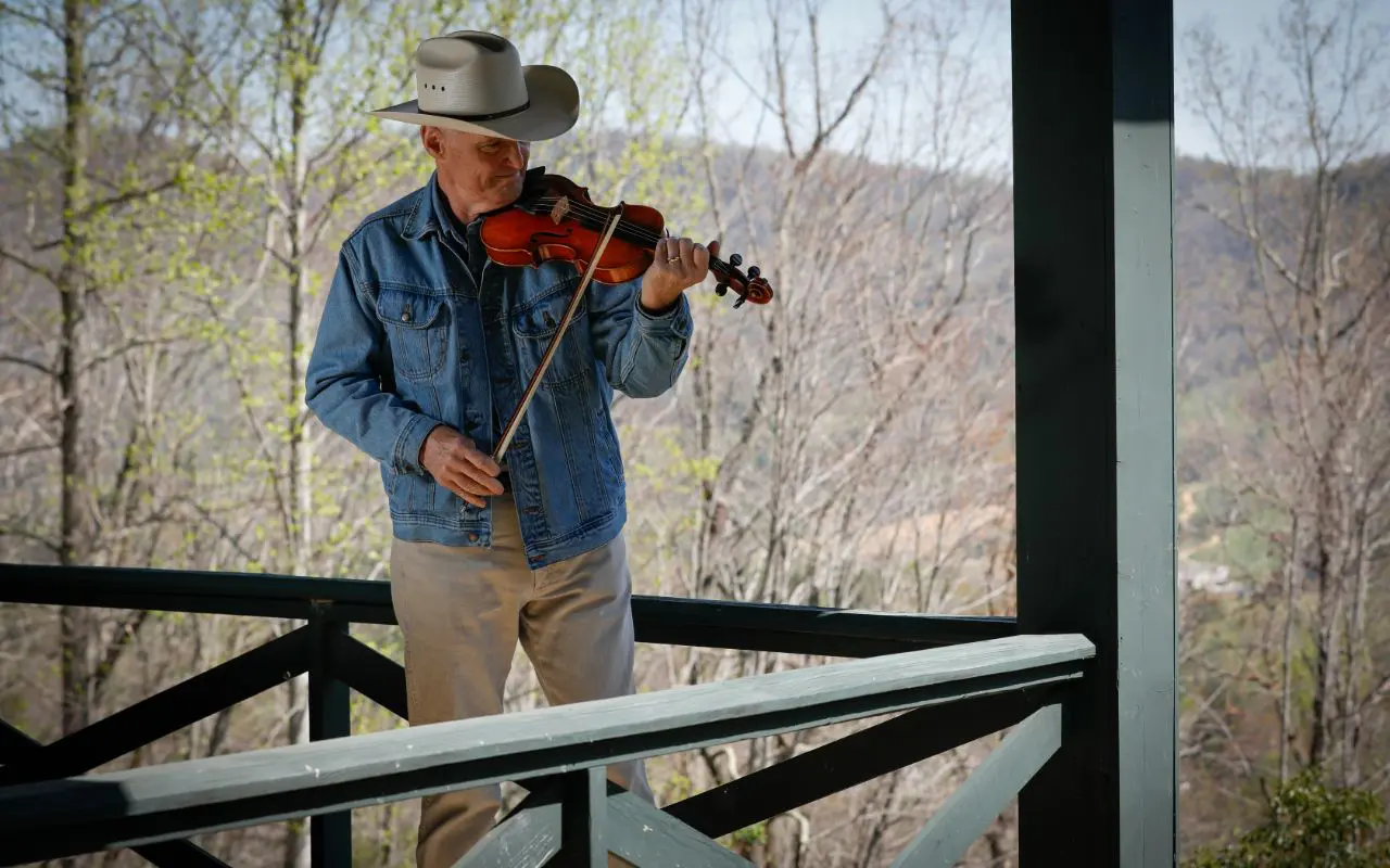 A man playing the violin on top of a balcony.