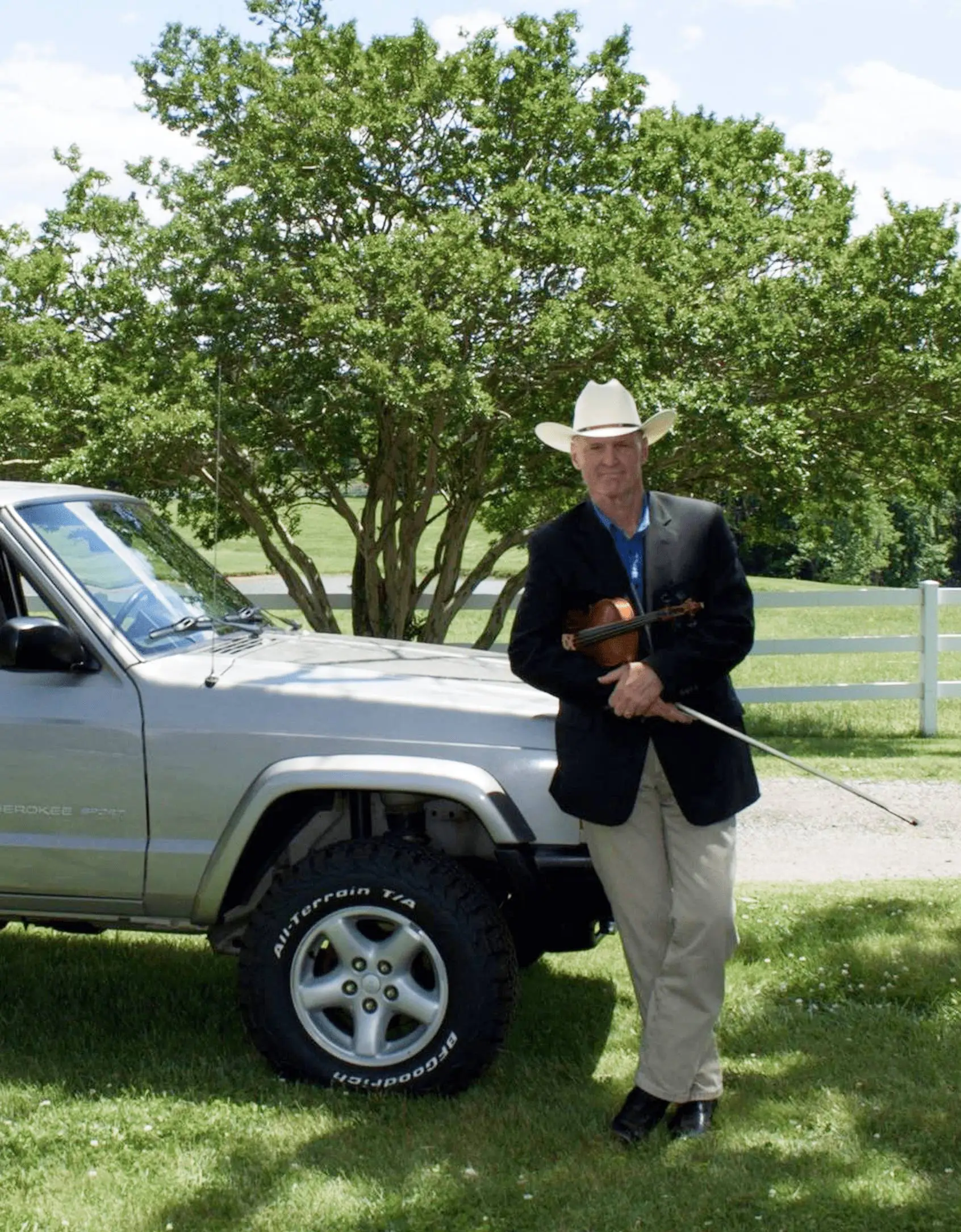 Tim A man standing next to a truck in the grass.